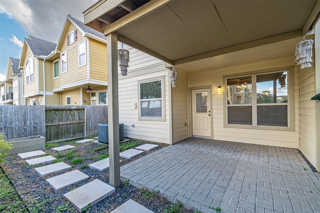 entrance to property featuring fence, a residential view, cooling unit, and a patio
