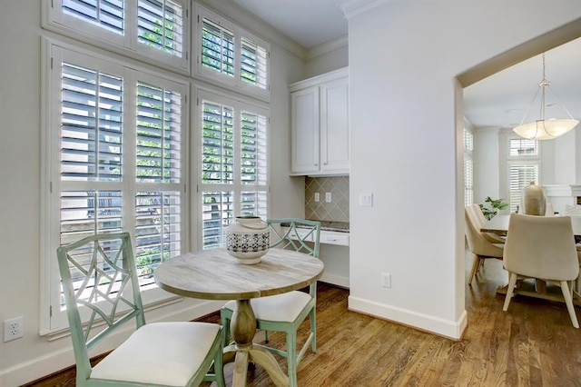 dining room featuring baseboards, ornamental molding, and light wood-style flooring