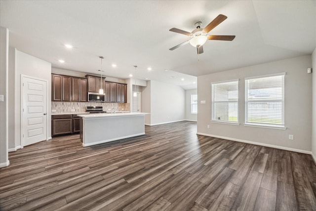 kitchen featuring dark wood-style floors, stainless steel appliances, light countertops, backsplash, and open floor plan