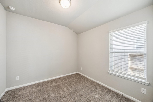 spare room featuring vaulted ceiling, carpet flooring, and baseboards
