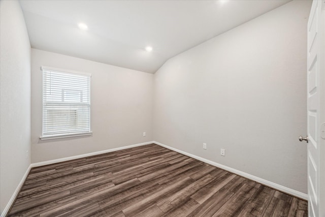 empty room with dark wood finished floors, vaulted ceiling, and baseboards