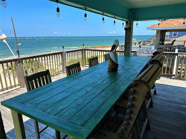 deck featuring outdoor dining area, a view of the beach, and a water view