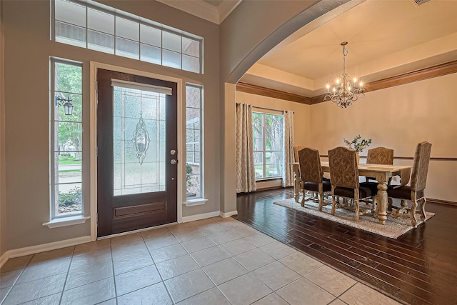 tiled foyer entrance featuring baseboards, arched walkways, and a notable chandelier