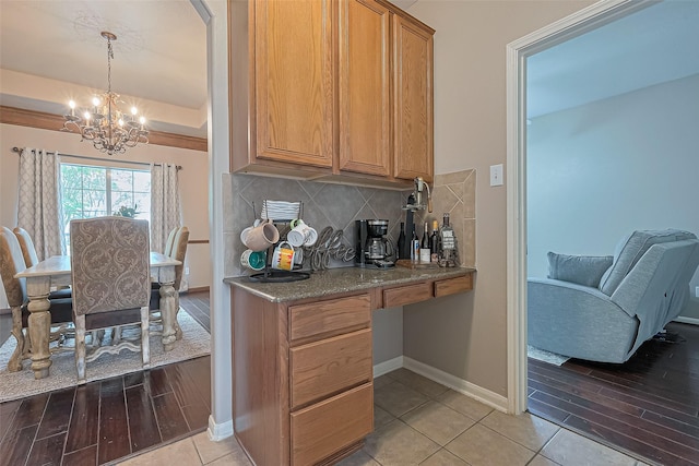 kitchen featuring a chandelier, baseboards, light wood-style flooring, and decorative backsplash