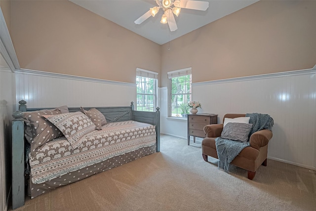 living area with a high ceiling, a ceiling fan, carpet flooring, and wainscoting
