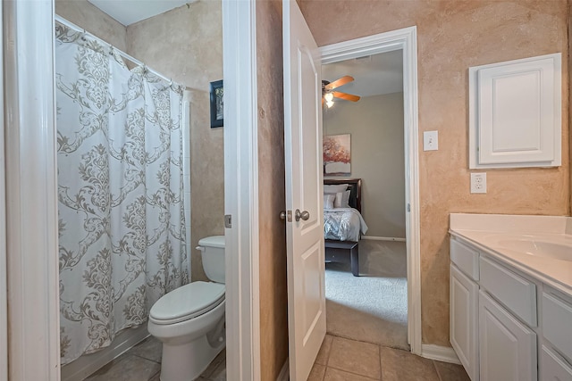 ensuite bathroom with ceiling fan, toilet, tile patterned floors, vanity, and ensuite bath