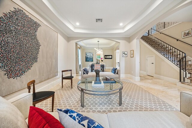 living area featuring crown molding, arched walkways, baseboards, and stairway