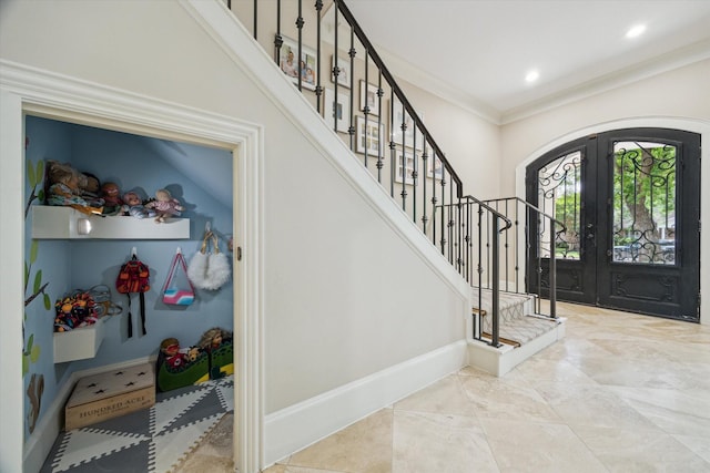 foyer featuring stairway, arched walkways, baseboards, and french doors