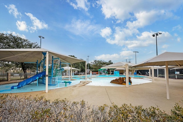 pool with fence, a patio area, and a water play area