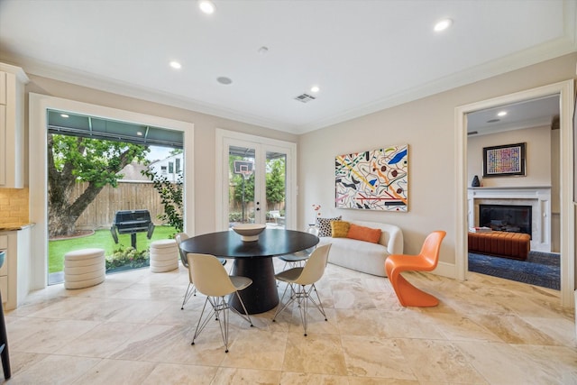 dining room featuring crown molding, a glass covered fireplace, visible vents, and french doors