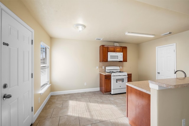 kitchen with brown cabinetry, white appliances, light countertops, baseboards, and visible vents