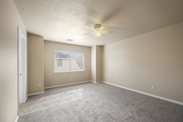 empty room featuring light carpet, a ceiling fan, visible vents, and baseboards
