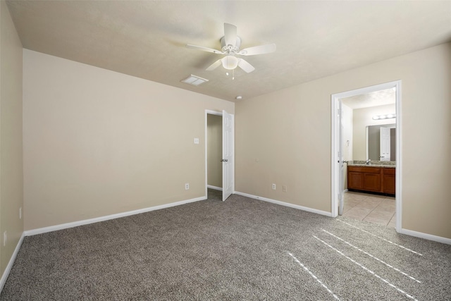 unfurnished bedroom featuring ensuite bath, visible vents, baseboards, and light carpet
