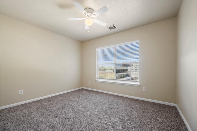 carpeted spare room featuring baseboards, a ceiling fan, and visible vents