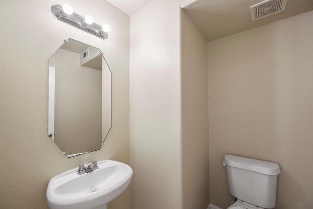 bathroom featuring toilet, a sink, and visible vents