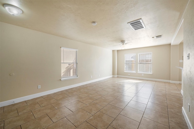 unfurnished room featuring a ceiling fan, a textured ceiling, light tile patterned floors, baseboards, and visible vents
