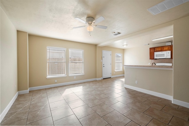 unfurnished room with baseboards, a ceiling fan, visible vents, and light tile patterned floors