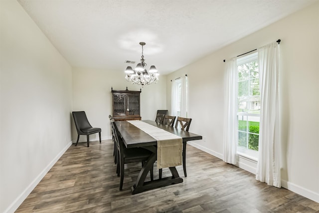 dining space with wood finished floors, visible vents, baseboards, and a notable chandelier