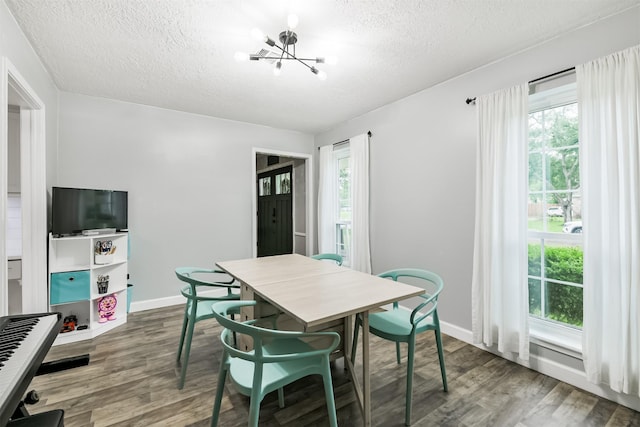 dining area with baseboards, wood finished floors, a textured ceiling, and a chandelier