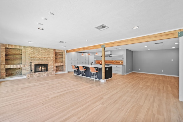 unfurnished living room featuring recessed lighting, visible vents, light wood-style floors, baseboards, and a fireplace