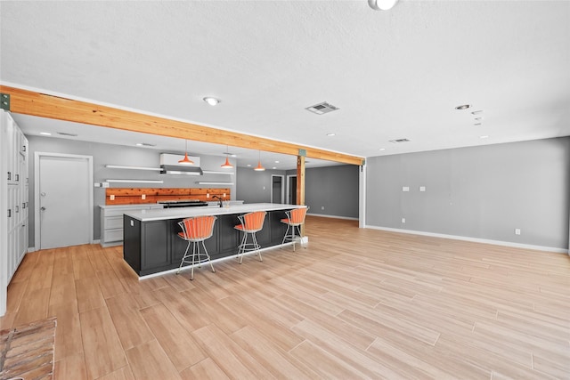 kitchen featuring baseboards, light countertops, visible vents, and a breakfast bar