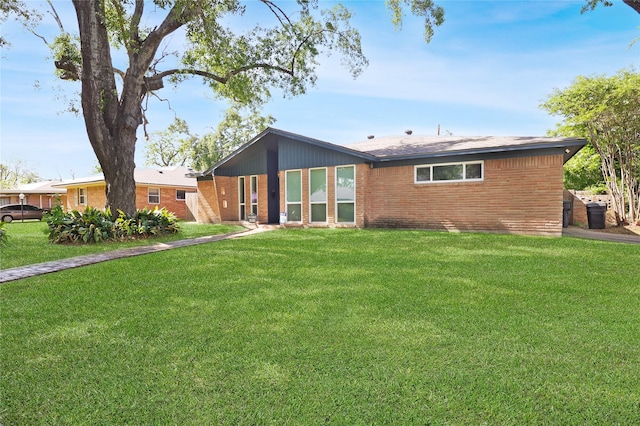 back of property with brick siding and a lawn