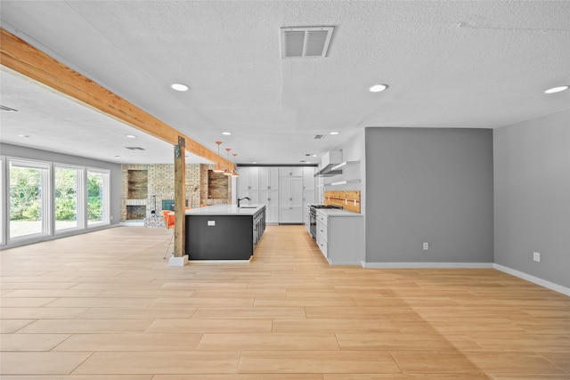 kitchen with light countertops, visible vents, light wood-type flooring, baseboards, and open floor plan