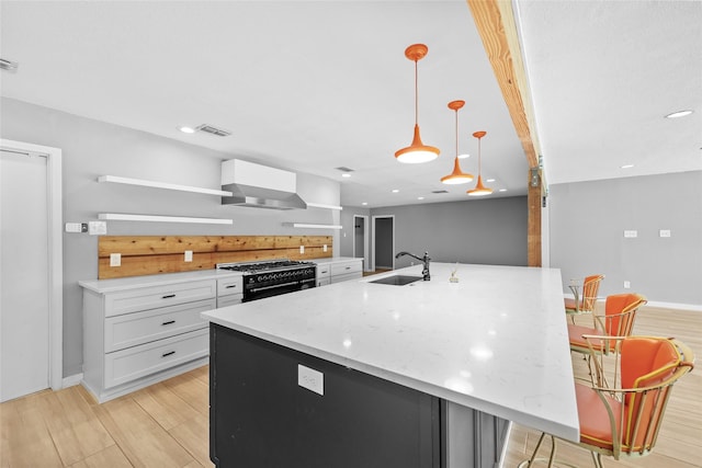 kitchen with a sink, visible vents, range with two ovens, wall chimney range hood, and open shelves
