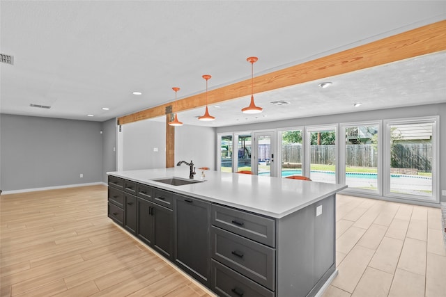 kitchen with a sink, open floor plan, a center island with sink, light countertops, and visible vents