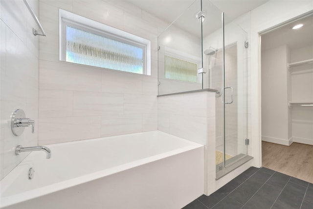 full bath with tile patterned floors, a stall shower, a spacious closet, a tub, and recessed lighting