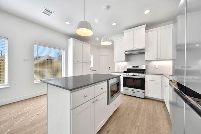 kitchen with under cabinet range hood, appliances with stainless steel finishes, visible vents, and light wood finished floors