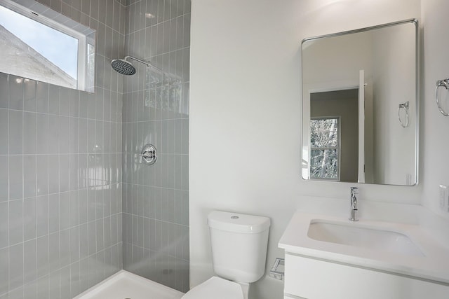 full bathroom with toilet, vanity, and tiled shower
