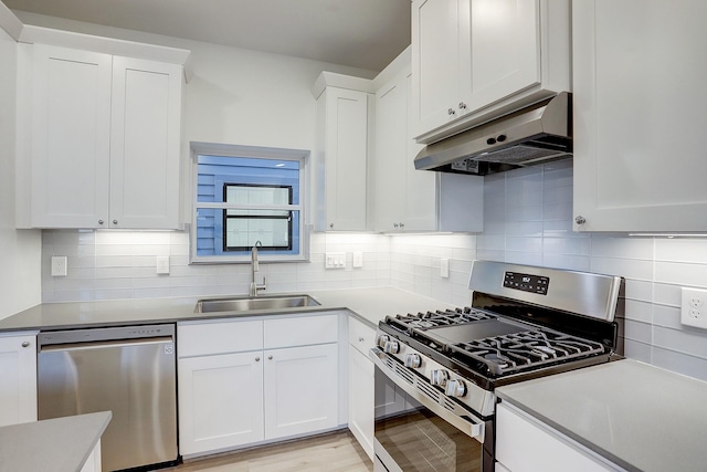 kitchen with decorative backsplash, under cabinet range hood, a sink, and appliances with stainless steel finishes