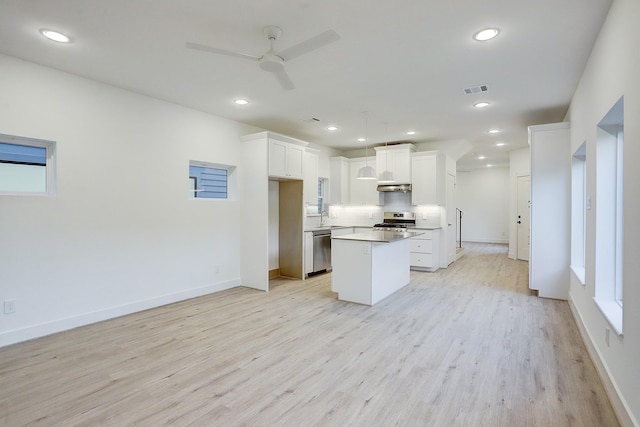 kitchen featuring light wood finished floors, stainless steel appliances, a sink, ceiling fan, and a kitchen island