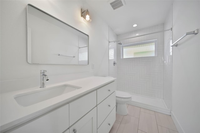 full bathroom with tiled shower, visible vents, vanity, and toilet