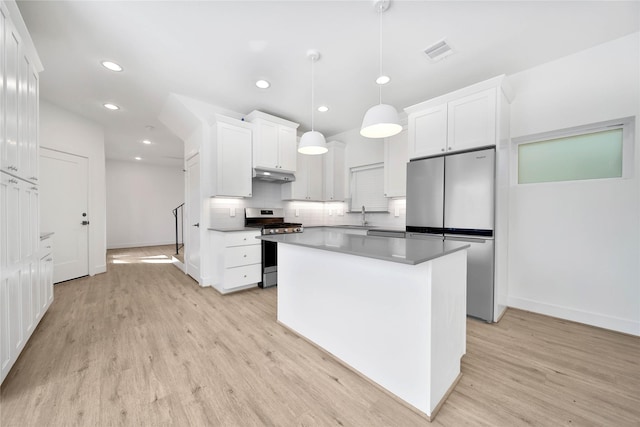 kitchen with a sink, stainless steel appliances, light wood finished floors, baseboards, and under cabinet range hood