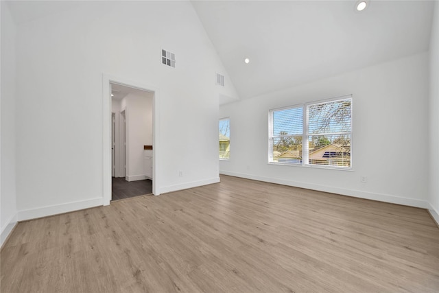 unfurnished living room featuring high vaulted ceiling, baseboards, light wood-style floors, and visible vents
