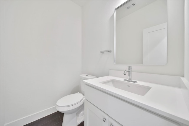 half bath featuring wood finished floors, visible vents, toilet, vanity, and baseboards