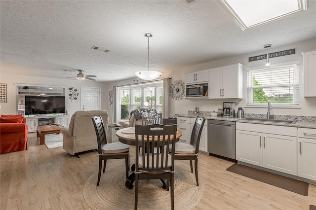 dining area with light wood-style flooring, visible vents, and a textured ceiling