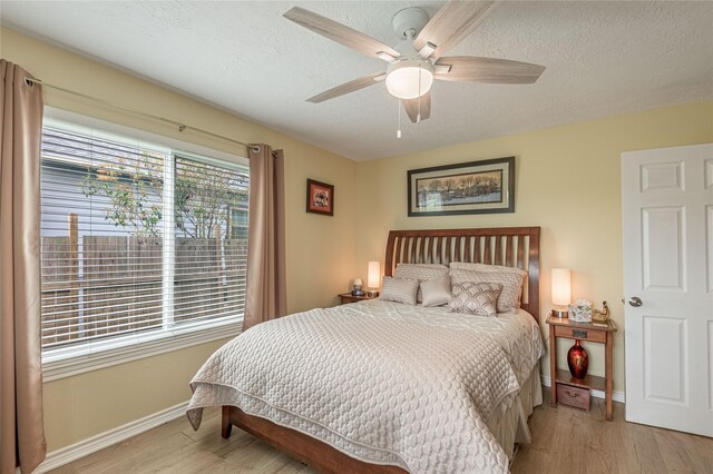 bedroom featuring baseboards, a textured ceiling, and light wood-style flooring