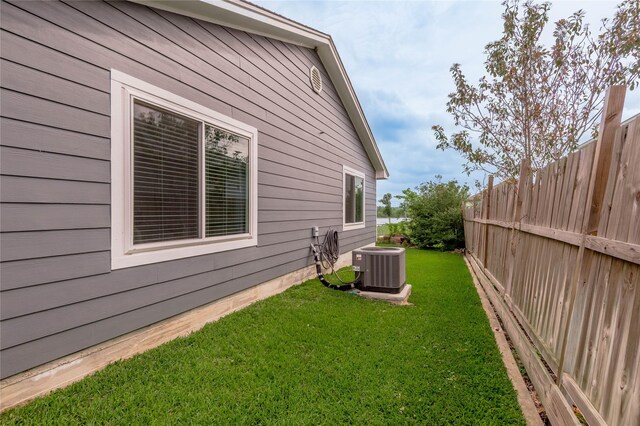 view of side of property featuring a lawn, fence, and cooling unit