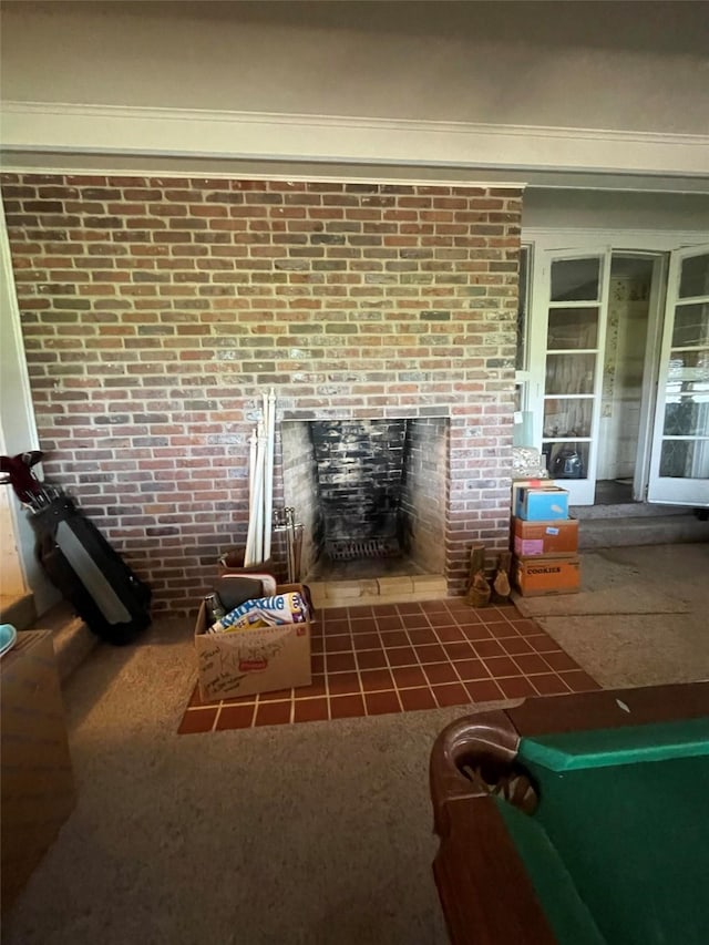 living area featuring a fireplace with flush hearth and brick wall