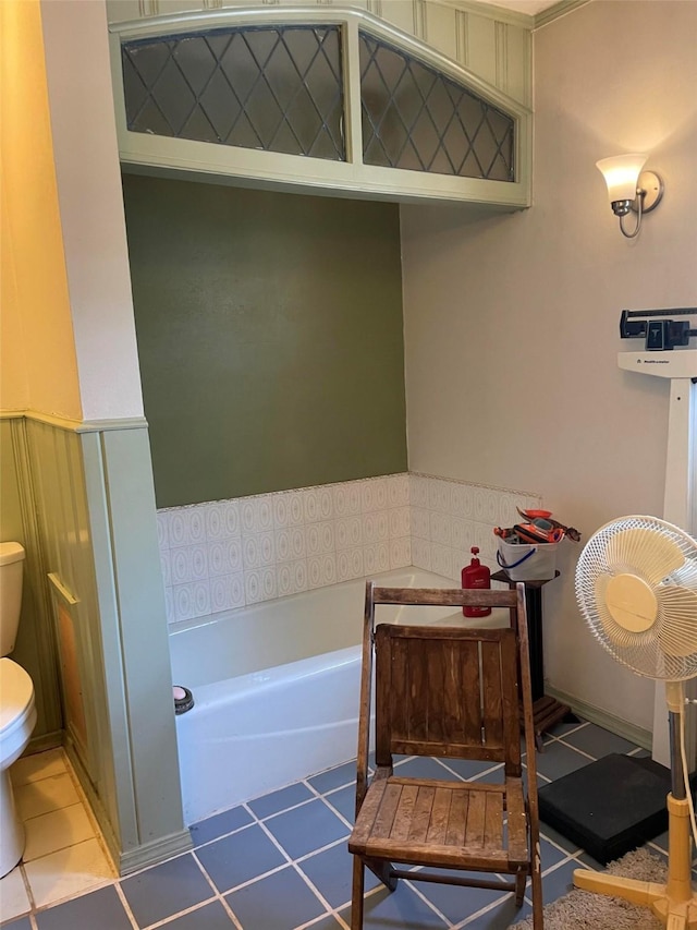 full bathroom with a bath, toilet, tile patterned flooring, and wainscoting