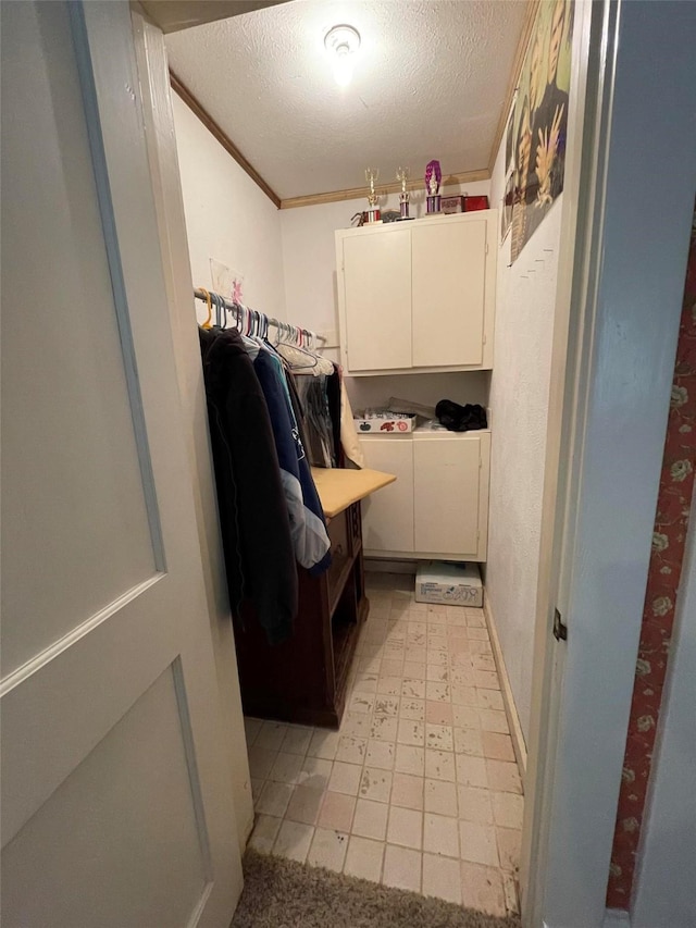 laundry area featuring light floors, ornamental molding, separate washer and dryer, cabinet space, and a textured ceiling