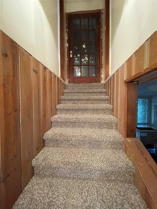 stairway featuring wainscoting and wood walls