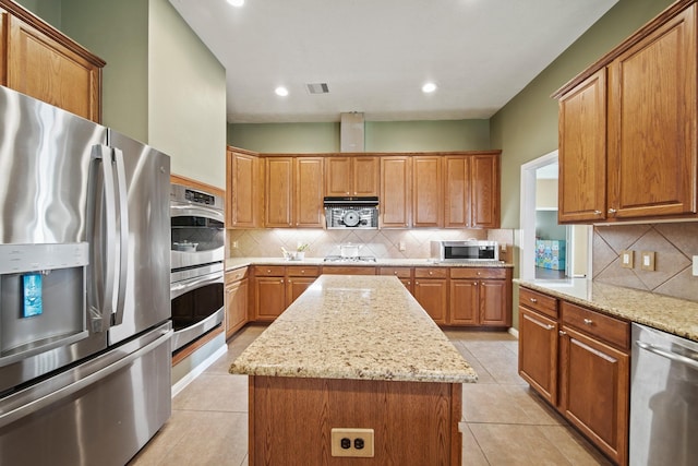 1704 Tempe St, League City, TX 77573 - kitchen with stainless steel appliances, a kitchen island, light stone counters, decorative backsplash, and recessed lighting