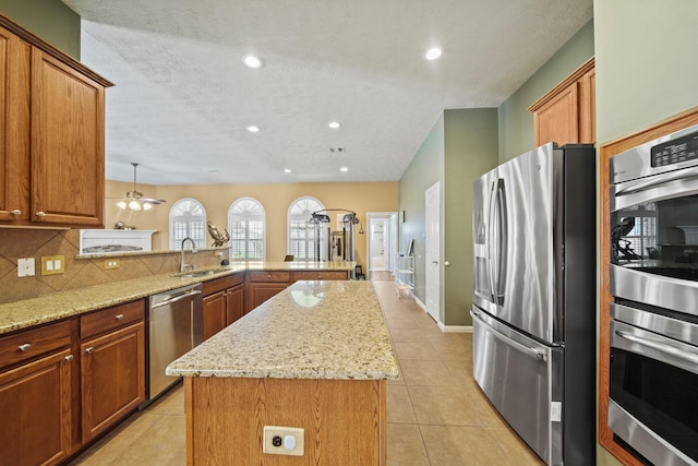 1704 Tempe St, League City, TX 77573 - kitchen featuring stainless steel appliances, a sink, a center island, a peninsula, and light stone counters
