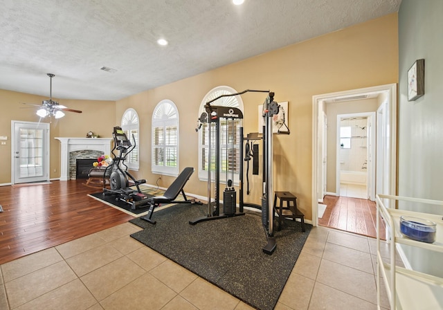 1704 Tempe St, League City, TX 77573 - workout room with tile patterned flooring, ceiling fan, a fireplace, a textured ceiling, and baseboards