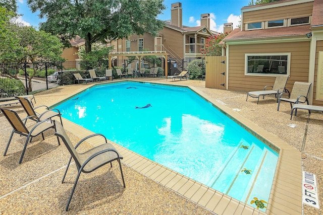 community pool featuring fence and a patio area