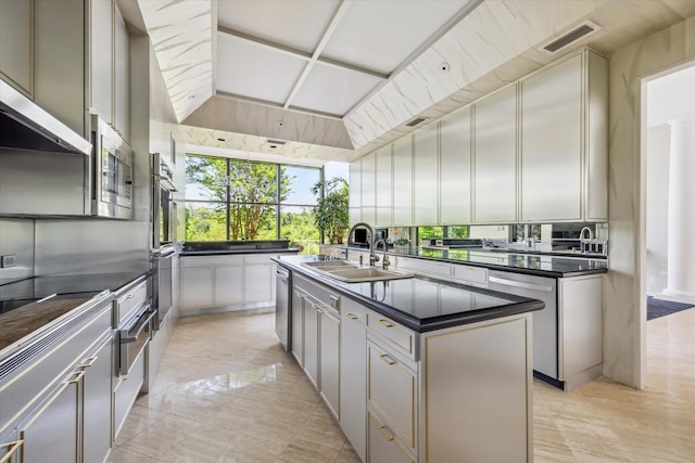 kitchen featuring visible vents, appliances with stainless steel finishes, dark countertops, a sink, and an island with sink